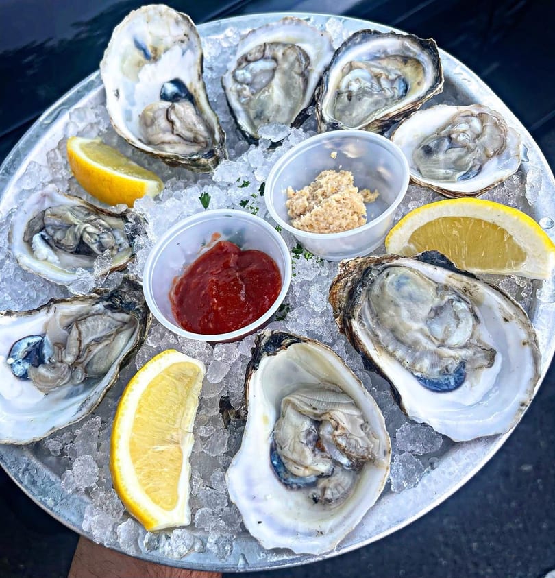 A dozen fresh oysters on the half shell, served on ice with lemon, cocktail sauce, and horseradish.